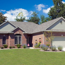 Beautiful brick ranch home against a blue cloudy sky.